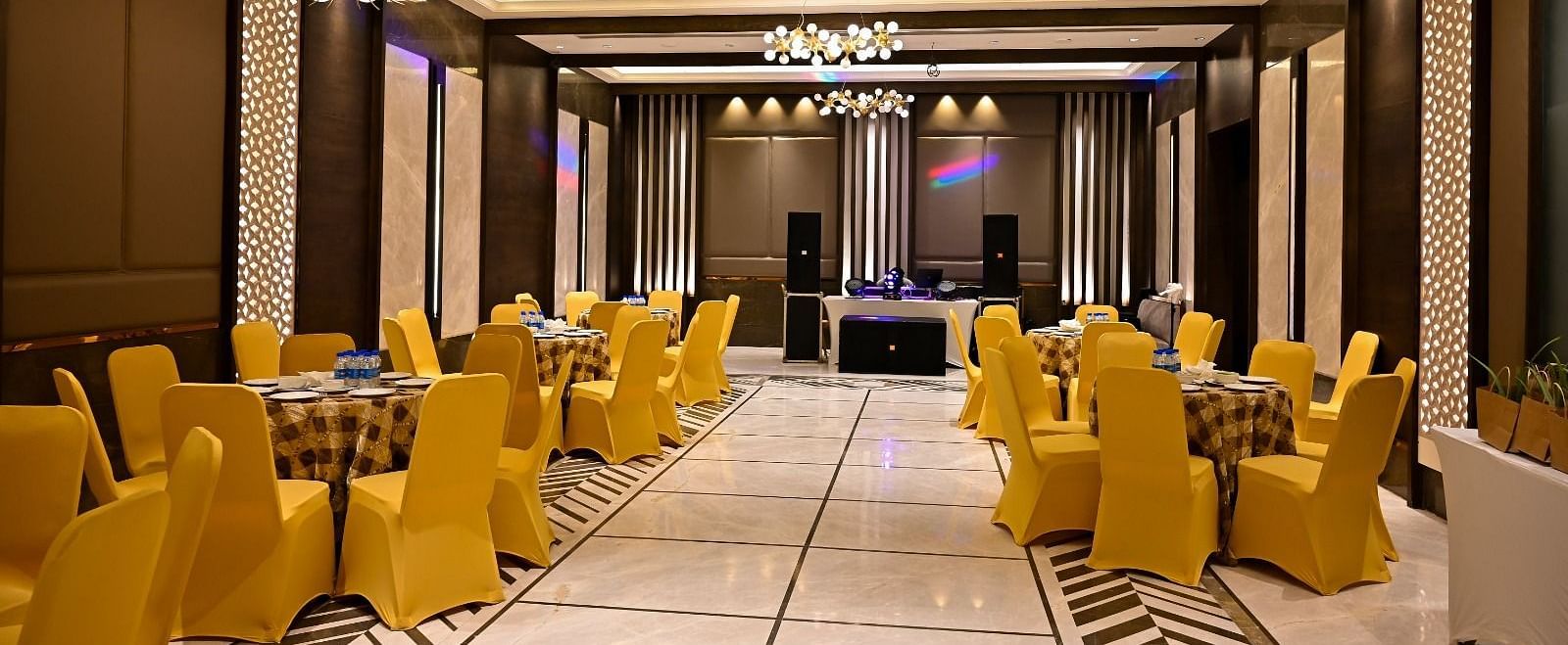 Event space with round tables and chairs arranged, featuring fancy lights hanging from the ceiling at BluSalzz Residence, Amritsar